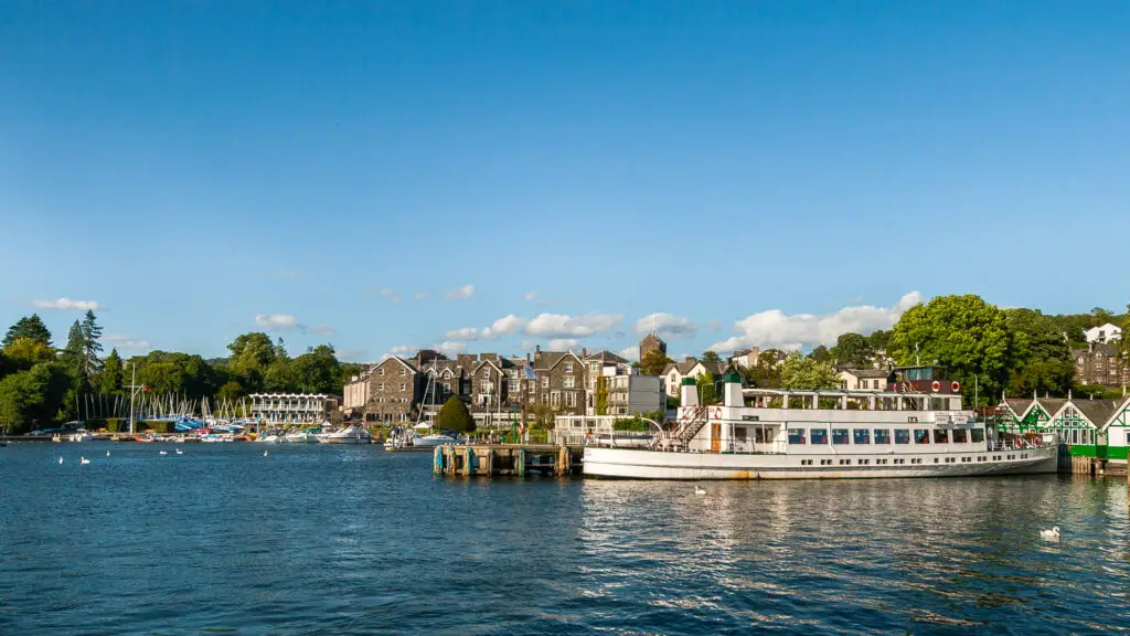 Cruise boats docked at Lake Windermere in Bowness-on-Windermere, showcasing scenic views of the serene lake and picturesque town in The Lake District, England.