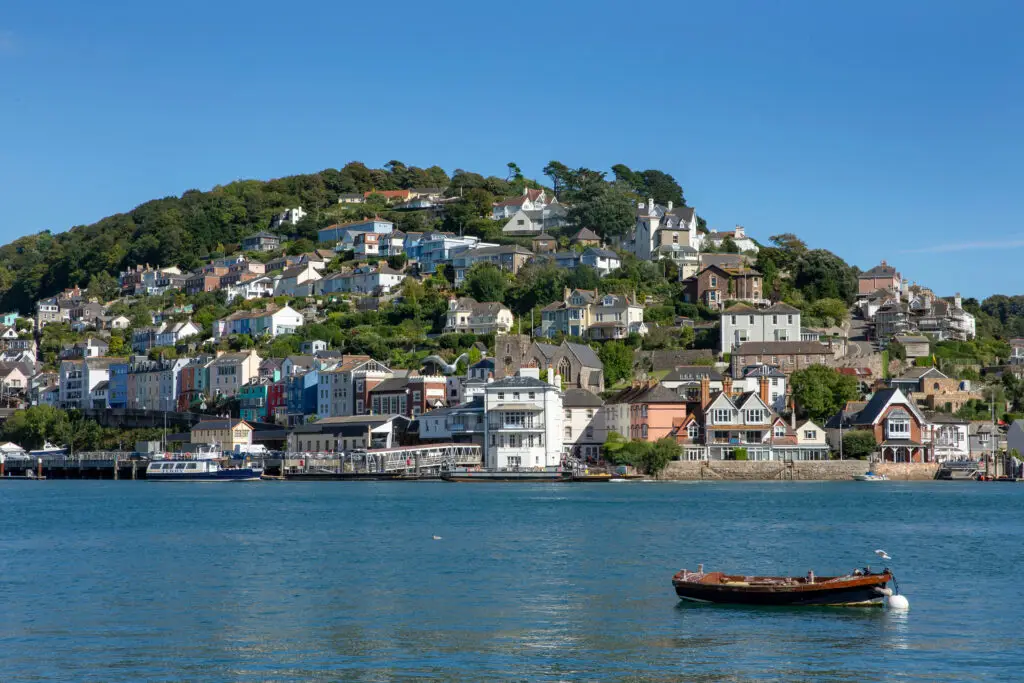Scenic view of St. Austell, Cornwall featuring coastal town architecture and homes climbing the hillside, under a clear blue sky - England tourism attraction.