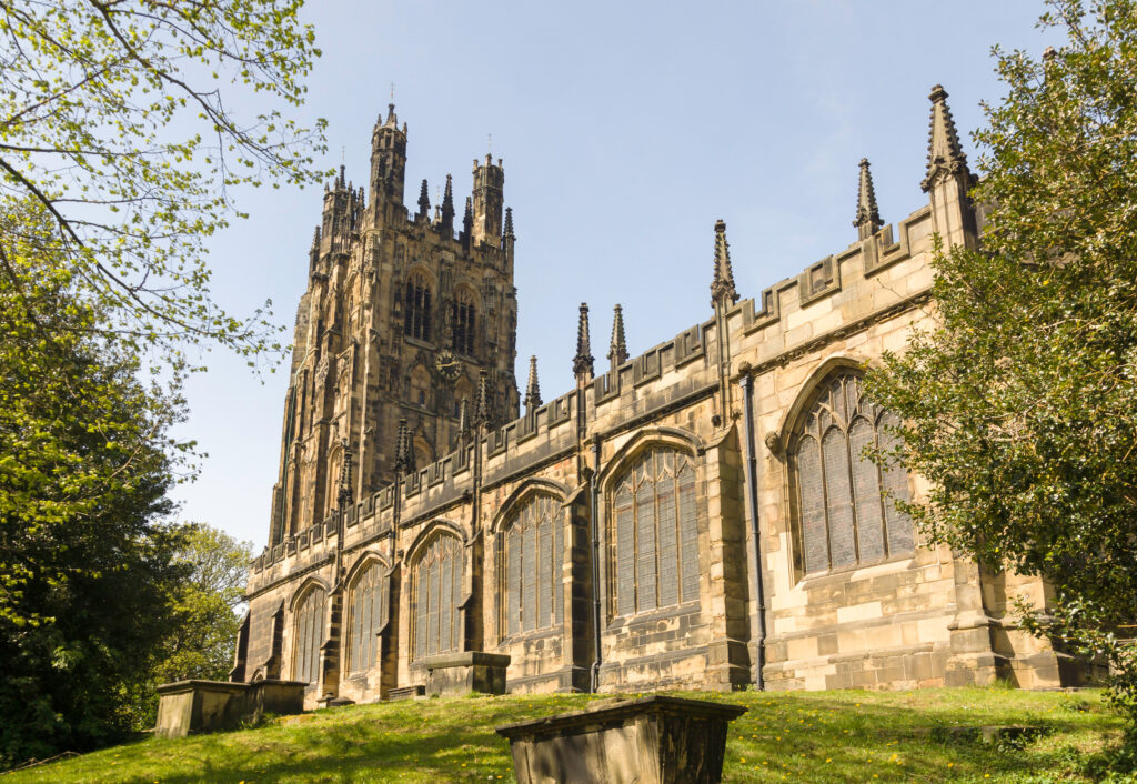 Saint Giles Church in Wrexham, a stunning example of medieval parish architecture from 1506, surrounded by greenery under a clear sky, Wales.