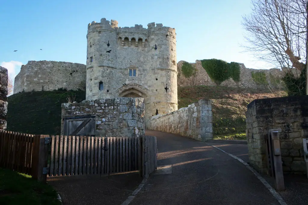Scenic view of Carisbrooke Castle entrance and ancient walls on a sunny day, Isle of Wight, England, highlighting a popular historic tourist attraction.
