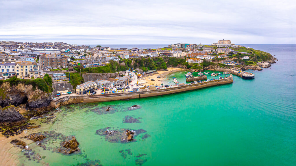 Aerial view of Newquay, Cornwall, showcasing the vibrant coastal town with turquoise waters, sandy beaches, and a bustling harbor.