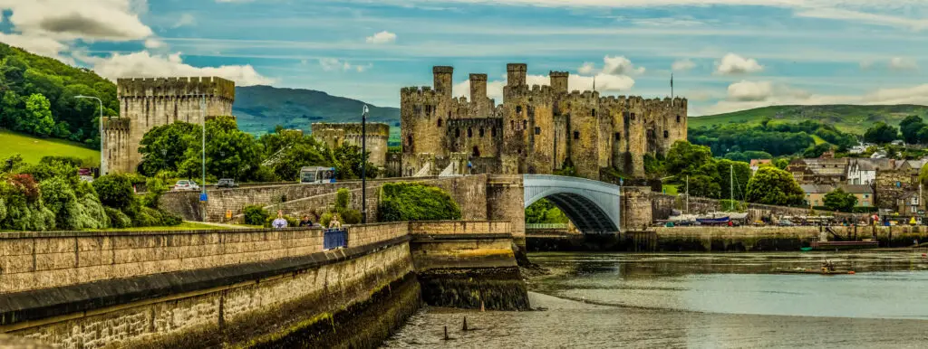 Panoramic view of Conwy Castle with surrounding landscape and bridge in North Wales, UK, a popular historical tourist attraction.
