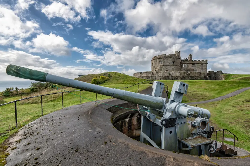 Historic Pendennis Castle in Falmouth, Cornwall, with foreground showing a large coastal defense cannon overlooking the sea.